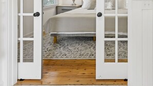 Un dormitorio con cama, mesita de noche, lámpara y ventana con persianas.