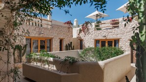 Un patio con muro de piedra, maceta integrada con plantas y un banco de madera.