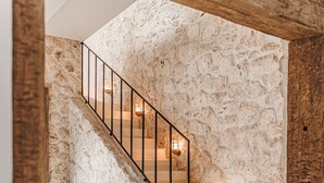 Una escalera con pared de piedra, paneles de madera y barandilla de metal.