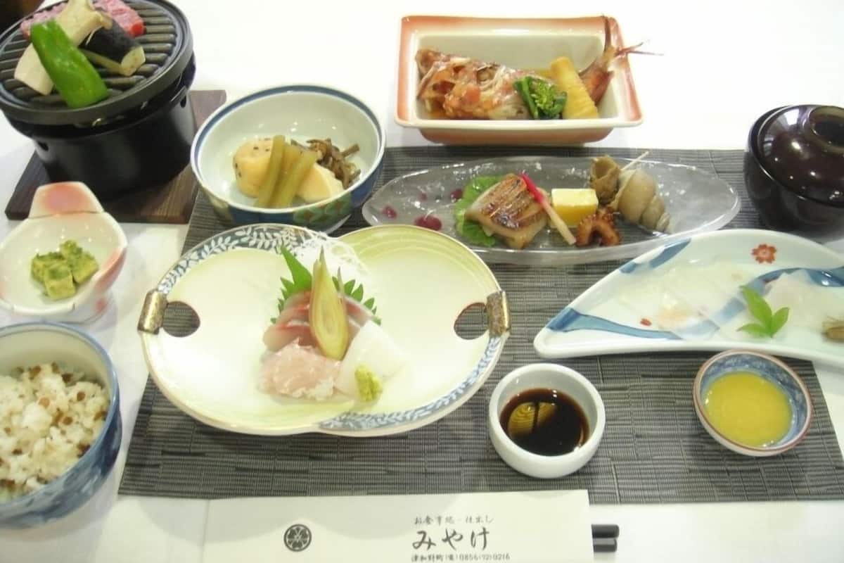 Variedad de platillos en una mesa, como sushi, sashimi y una olla caliente.