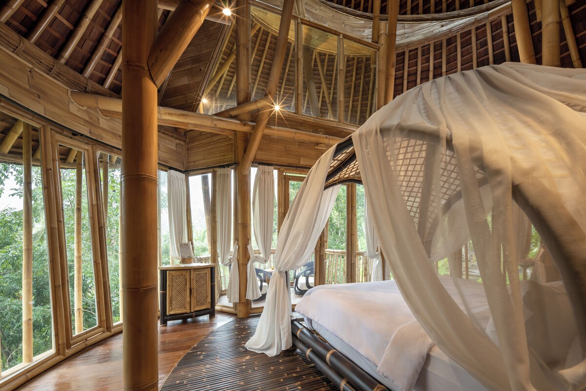 A room with a bed, large windows, and a wooden ceiling structure.