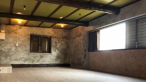 A spacious room with a wooden floor, a window with shutters, and a concrete wall. - Villa Gazamani (Yaese)