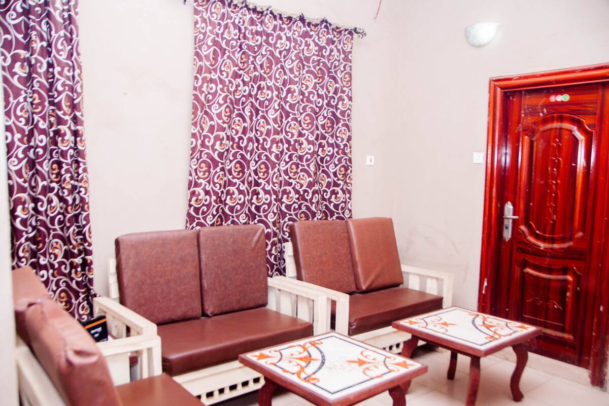 Una habitación con dos sofás de cuero marrón, una mesa de centro blanca y una puerta roja.