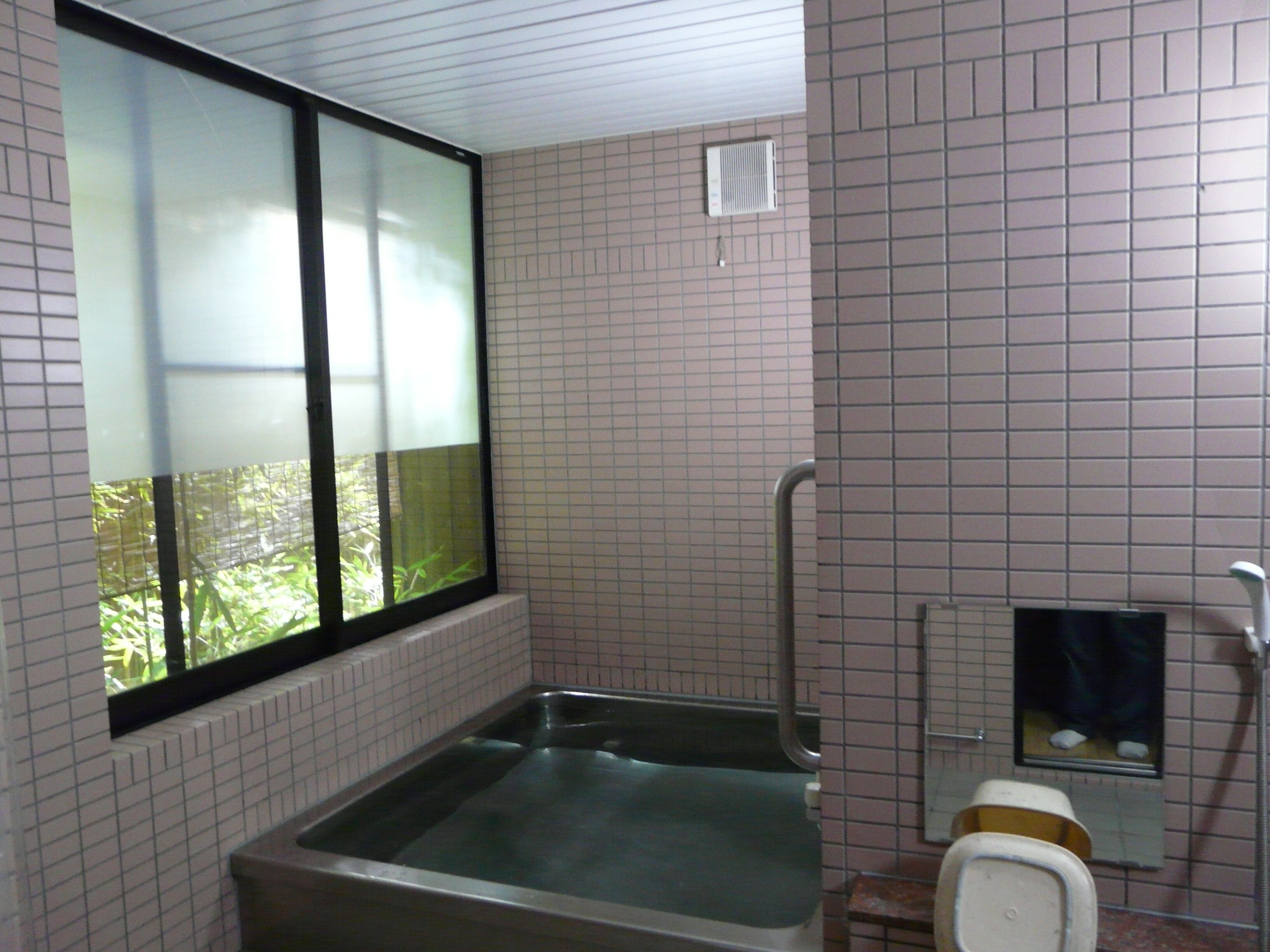 Un baño con ventana, bañera, inodoro y espejo.