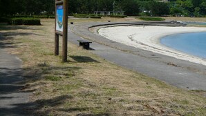 Ein Strand mit einem Holzschild, einem gewundenen Pfad und einer Bank.