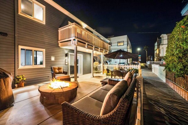 An outdoor patio with a fire pit, seating, and a covered area with tables and chairs.