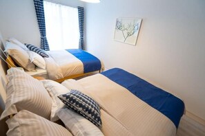 A bedroom with two beds, a window with curtains, and a wall-mounted picture. - Golden Drop S (Kin)