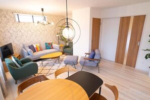 A modern living room with a sofa, armchairs, a coffee table, and a dining table. - Golden Drop S (Kin)