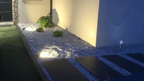 A modern building with a stone facade, a well-maintained gravel pathway, and a small garden area with a plant. - Quiet studio in the heart of Arradon (Arradon)