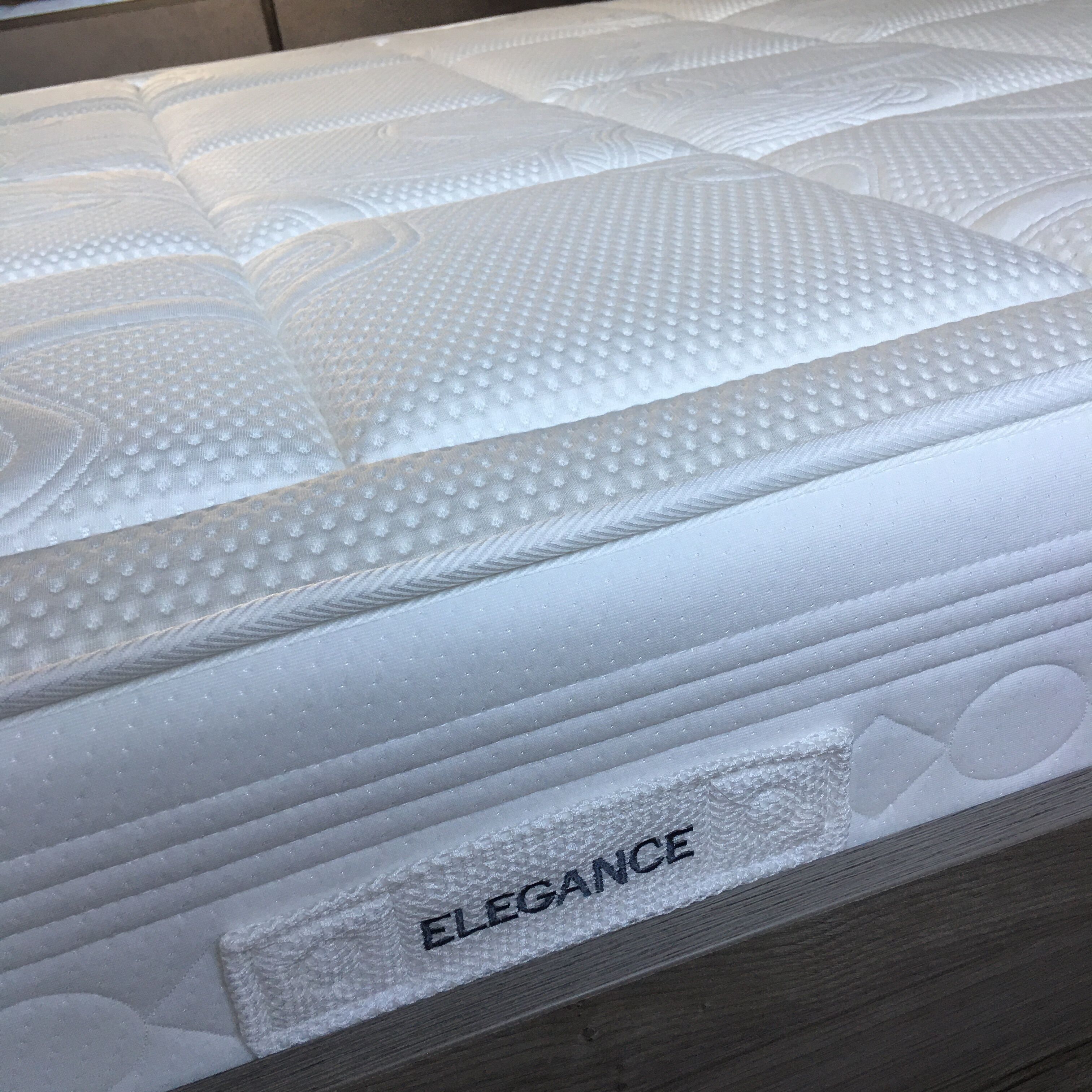 A mattress with a textured surface and the word "ELEGANCE" embossed on it.