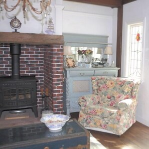 A room with a brick fireplace, a floral armchair, a dresser, and a mirror. - British Country House Brookfield Farm (Nasu)