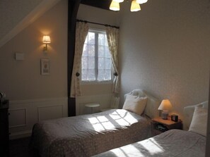 A bedroom with two beds, a window with curtains, a bedside table with a lamp, and a wall-mounted light fixture. - British Country House Brookfield Farm (Nasu)