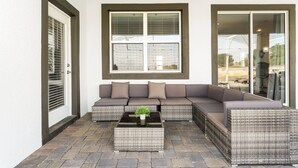 Un patio couvert avec un canapé d’angle, une table basse et des meubles en osier.