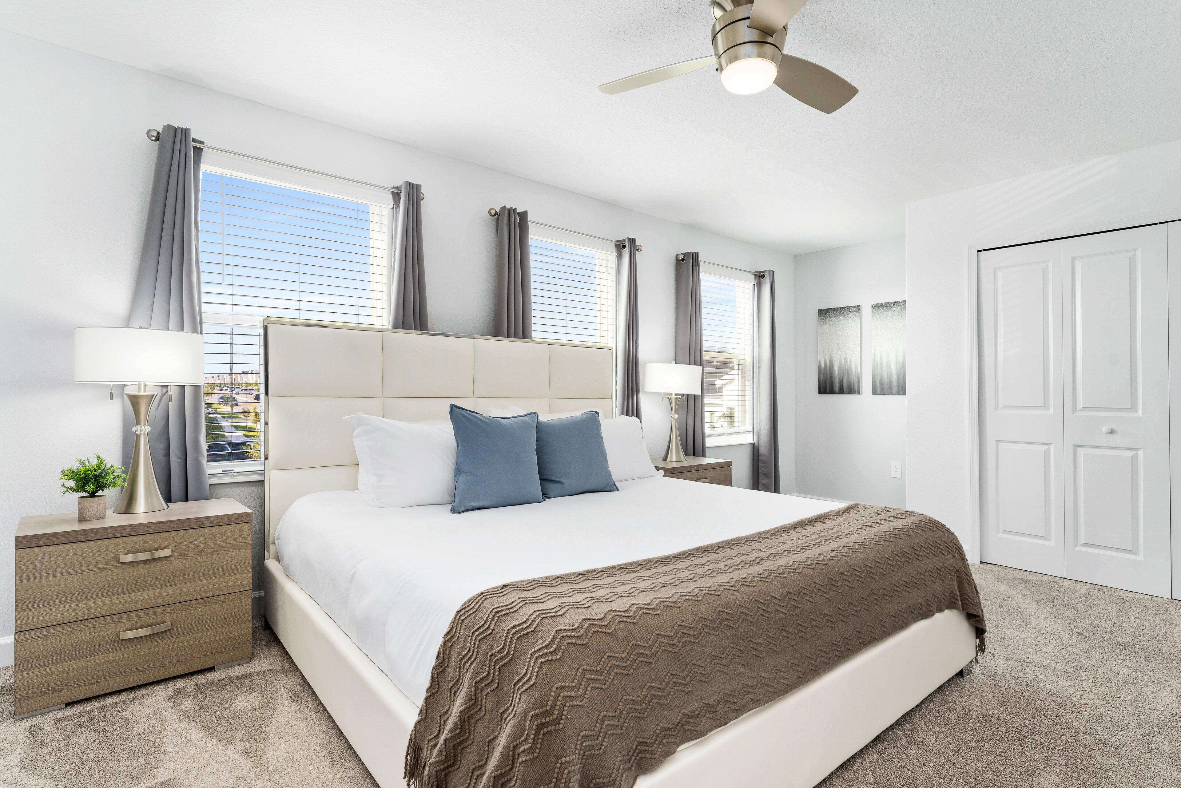 A modern hotel room with a large bed, a nightstand, a lamp, and a ceiling fan.