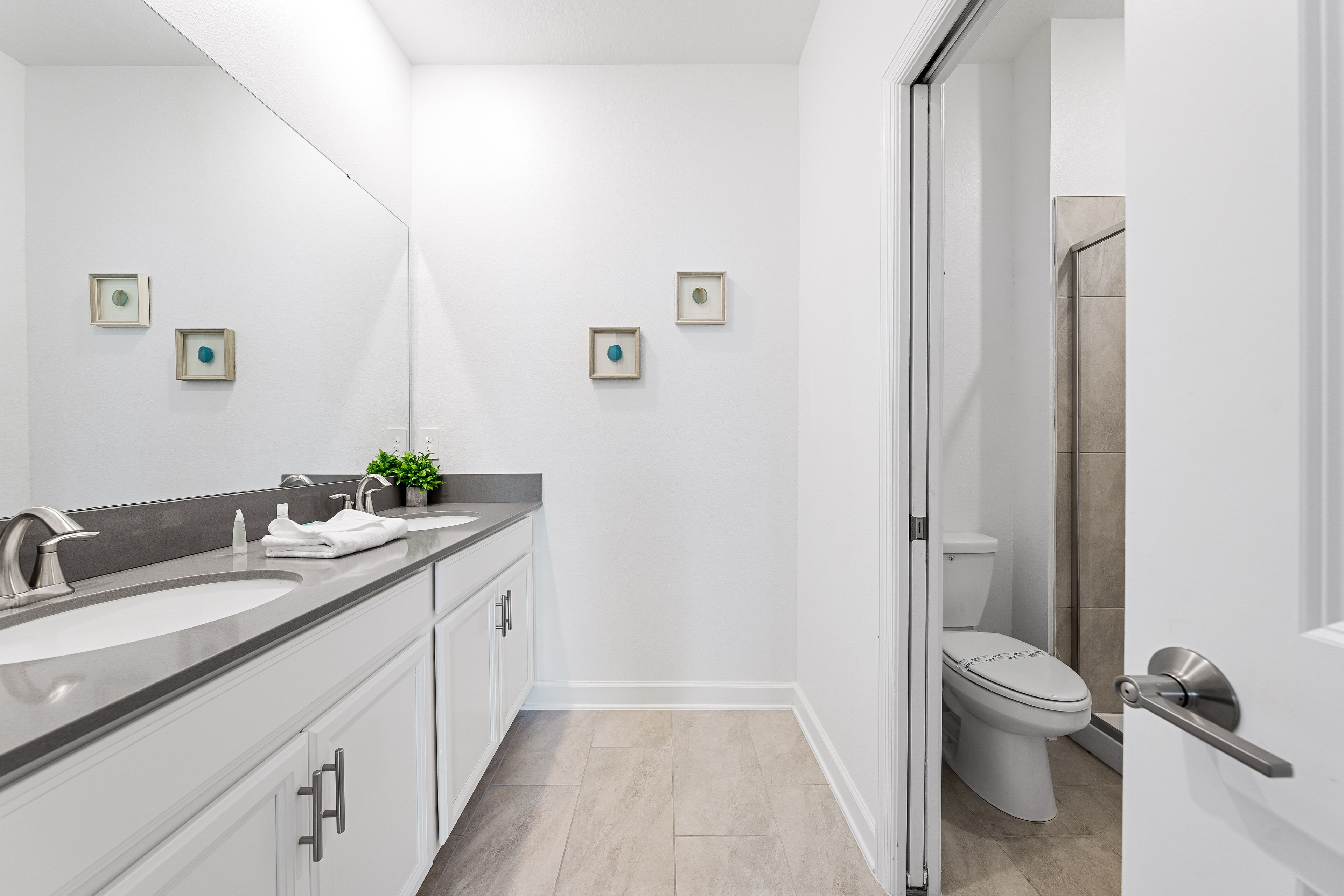 Ein modernes Badezimmer mit einem Doppelwaschbecken, einer Toilette und einer Dusche.