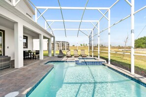 Una piscina con un porche cubierto, mobiliario exterior y vistas del paisaje circundante.
