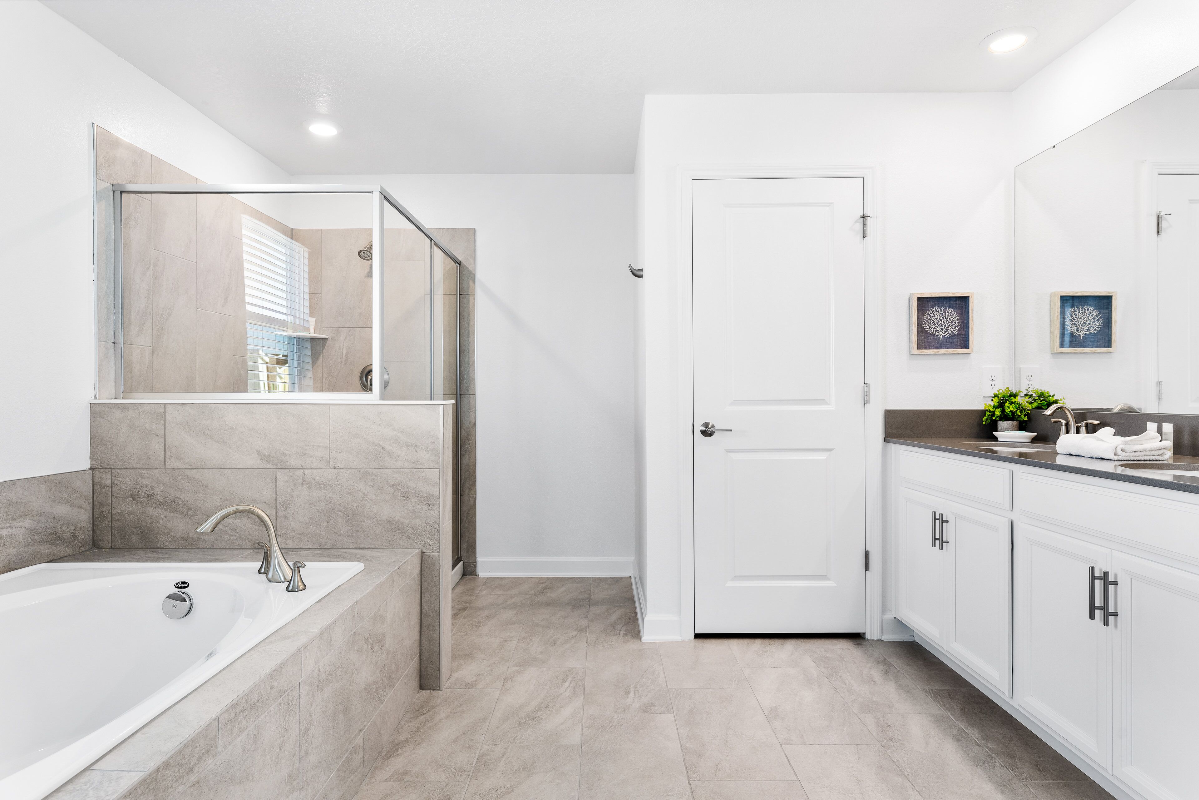 A modern bathroom with a large bathtub, a glass shower enclosure, and white cabinetry.