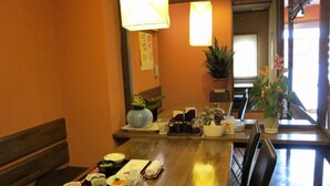Un comedor con una mesa de madera para dos, un florero y una planta en maceta.