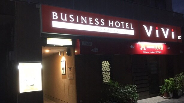 Un edificio con un letrero que dice 'Business Hotel' y un letrero 'Vivi' sobre la entrada.