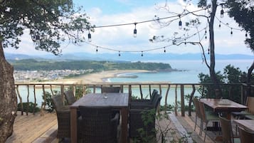 An outdoor seating area with wicker furniture overlooking a coastal landscape.