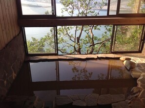A room with a large window overlooking a body of water and trees.
