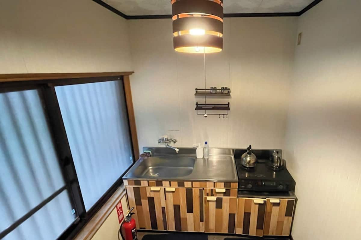 A compact kitchen with a sink, stove, and wooden storage unit.