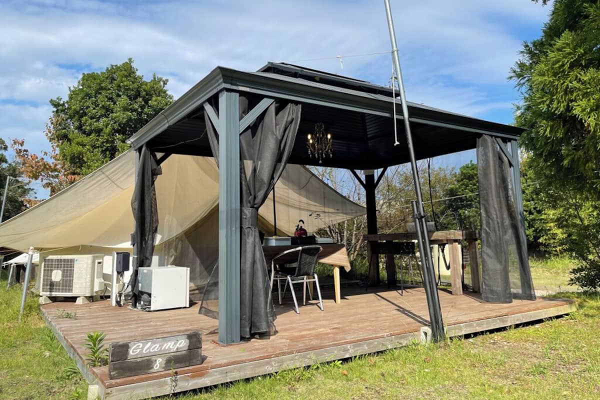 A covered outdoor area with a table and chairs, a sign labeled 'Clamp 8', and a large tent-like structure.