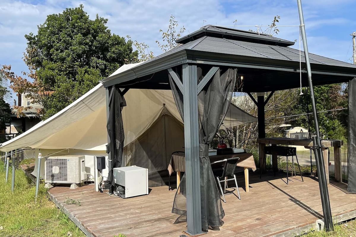 A covered outdoor area with a table and chairs, a grill, and a tent.