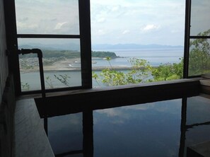 A room with a large window overlooking a coastal landscape, including a beach and distant mountains. - Yamamizuki (Shimanto)
