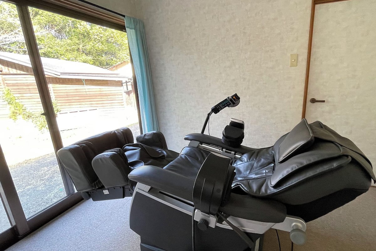 A massage chair in a room with a sliding glass door leading to an outdoor area.