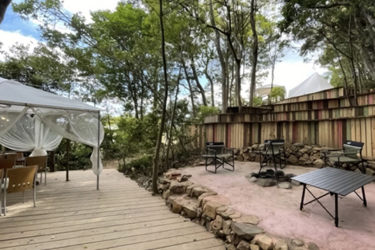 An outdoor patio with a white canopy, wooden deck, and seating area with chairs and a table.