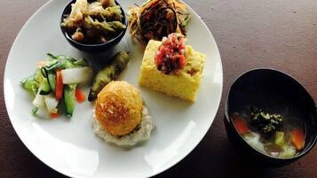A plate with various food items including a salad, a bread roll, a small bowl of soup, and a piece of cake.