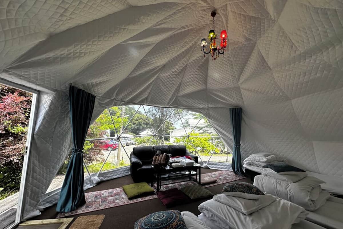 A tented room with a black sofa, a coffee table, and a bed.