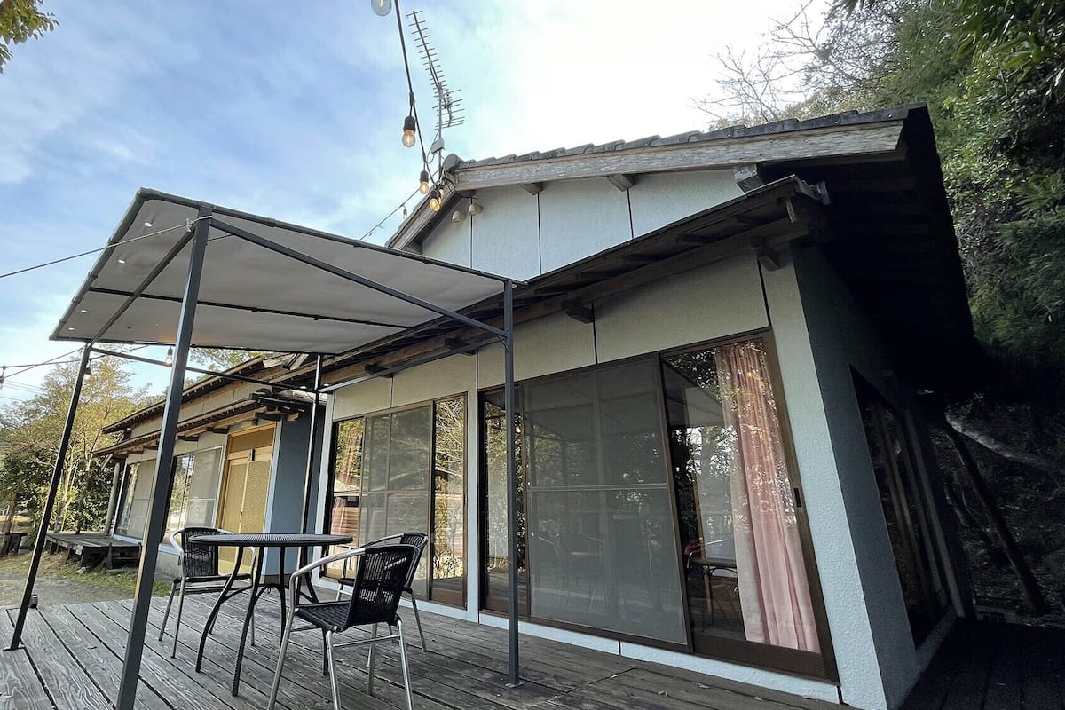 A modern house with a covered patio, large windows, and a wooden deck.