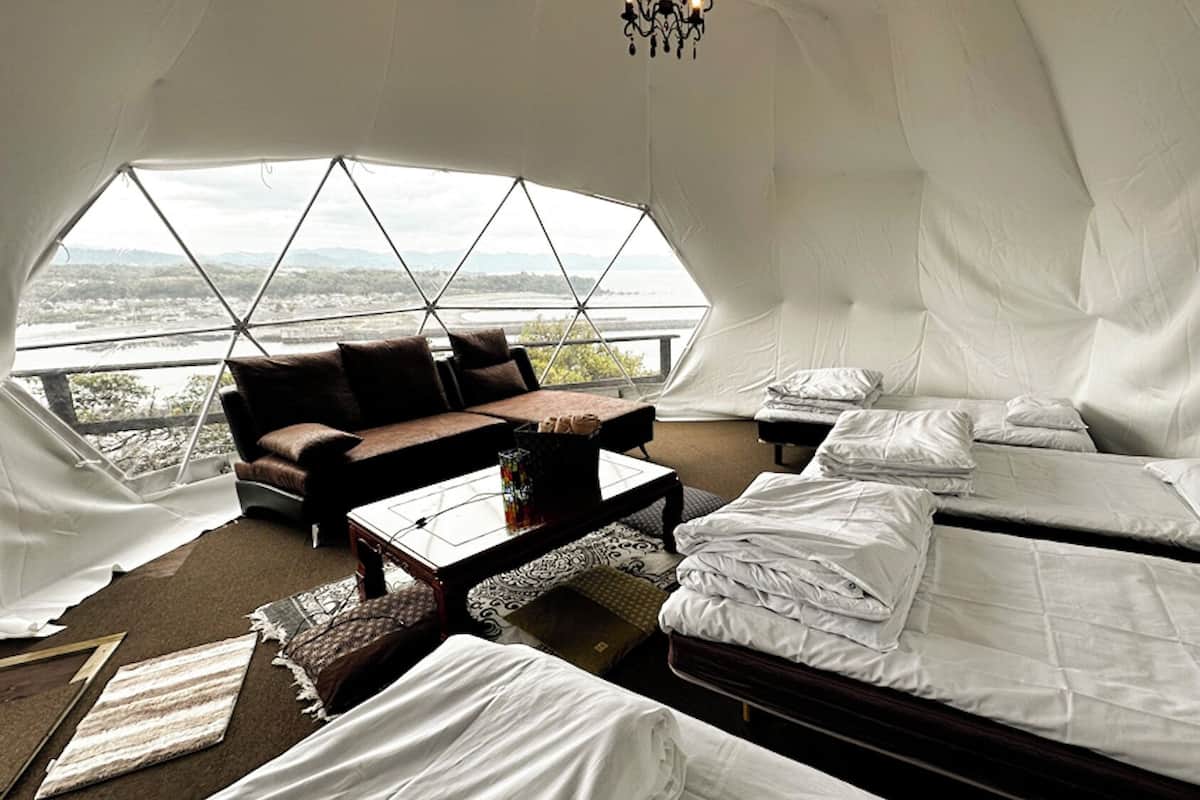 A tented accommodation with a sofa, a small table, and two beds.