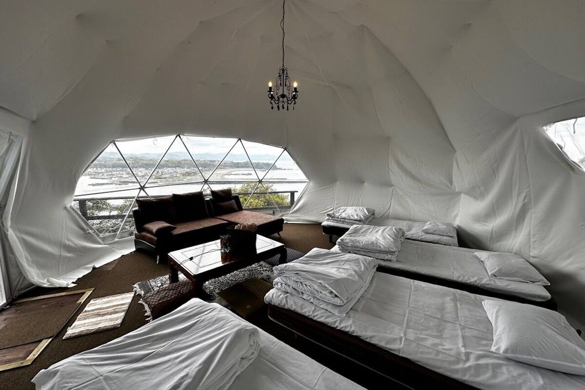 A tented accommodation with a bed, a sofa, and a chandelier.