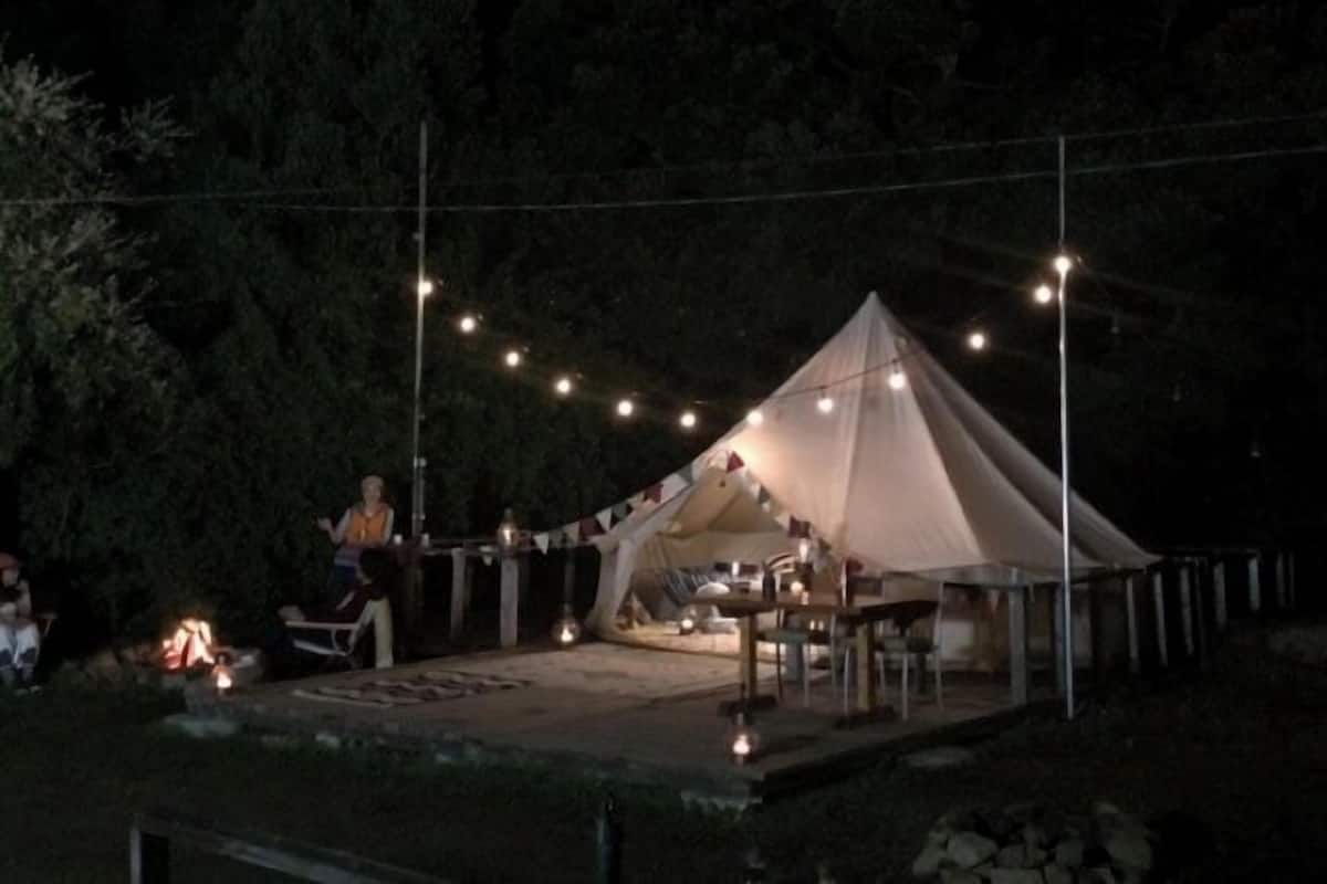 A tent with a table and chairs set up outside at night.
