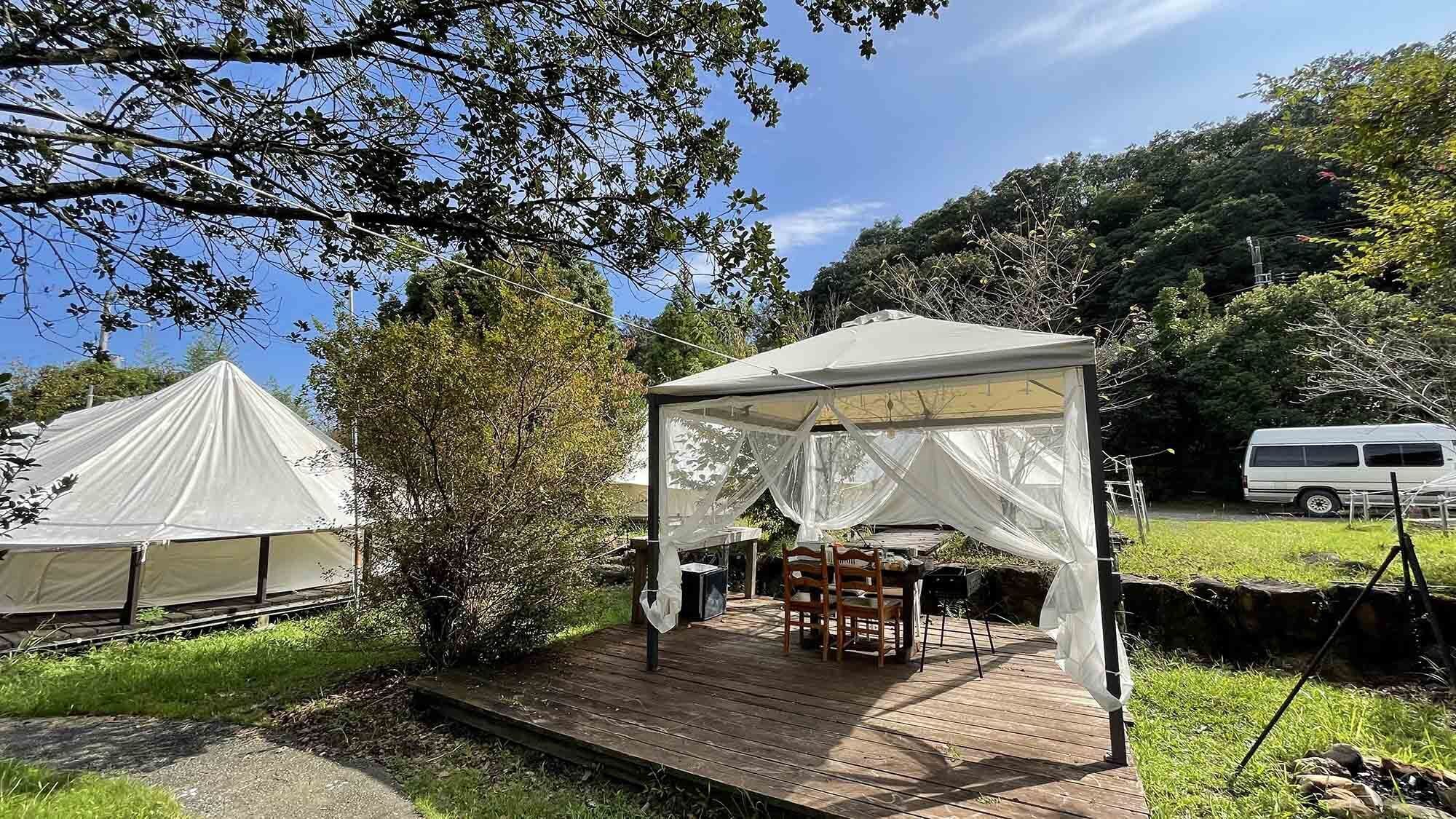 Ein überdachter Außenbereich mit Holzterrasse, Tischen und Stühlen.