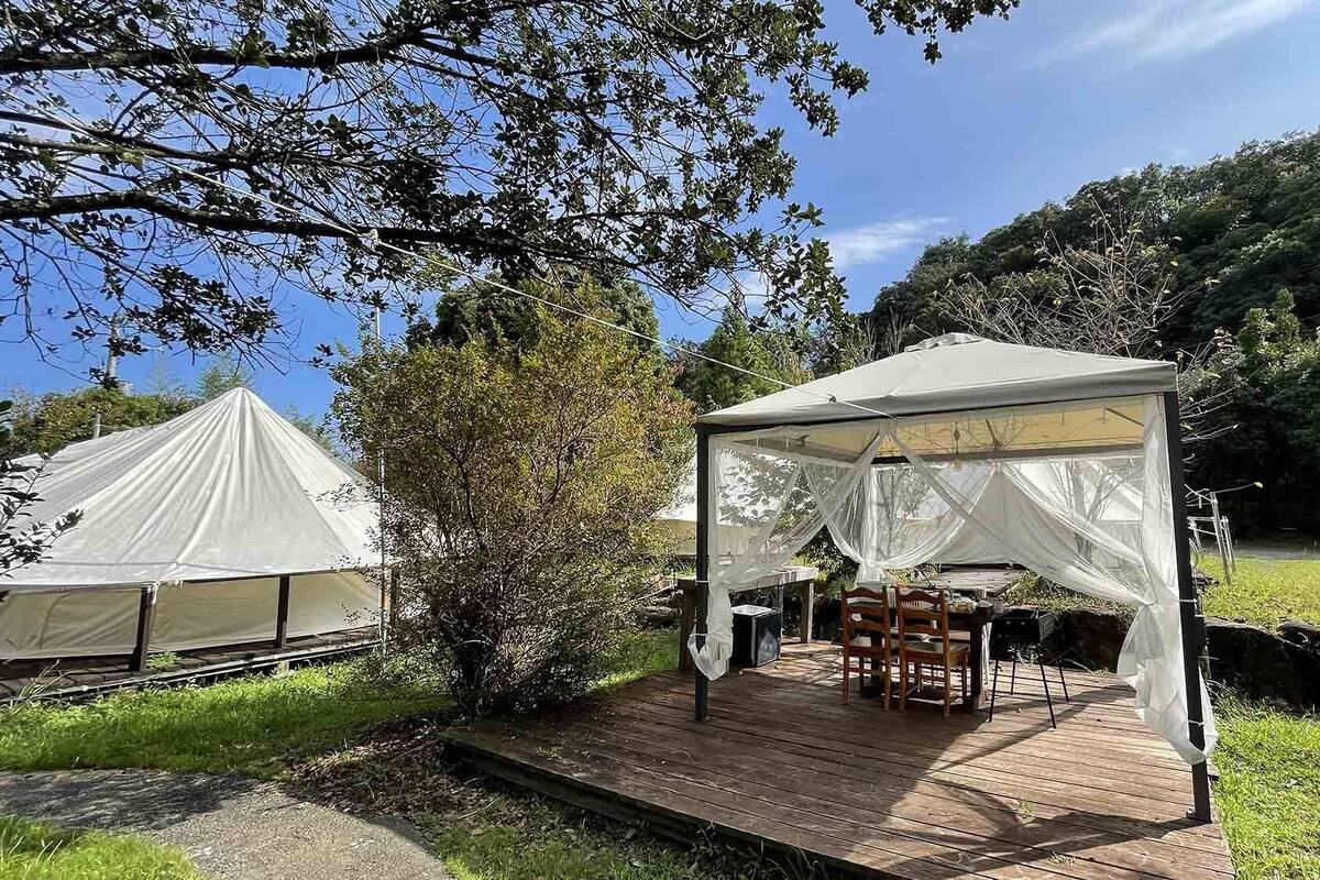 A tented outdoor area with a wooden deck, tables, and chairs.