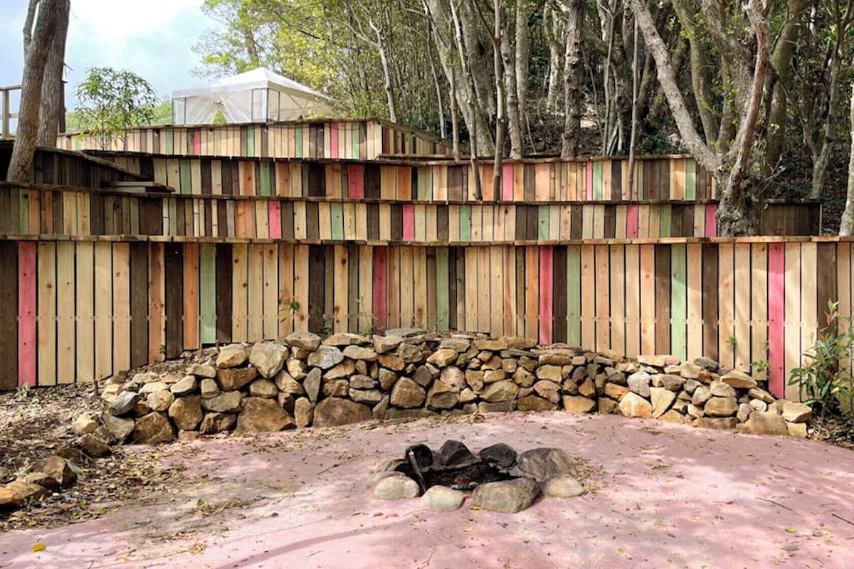 A wooden fence with a stone wall and a covered area.