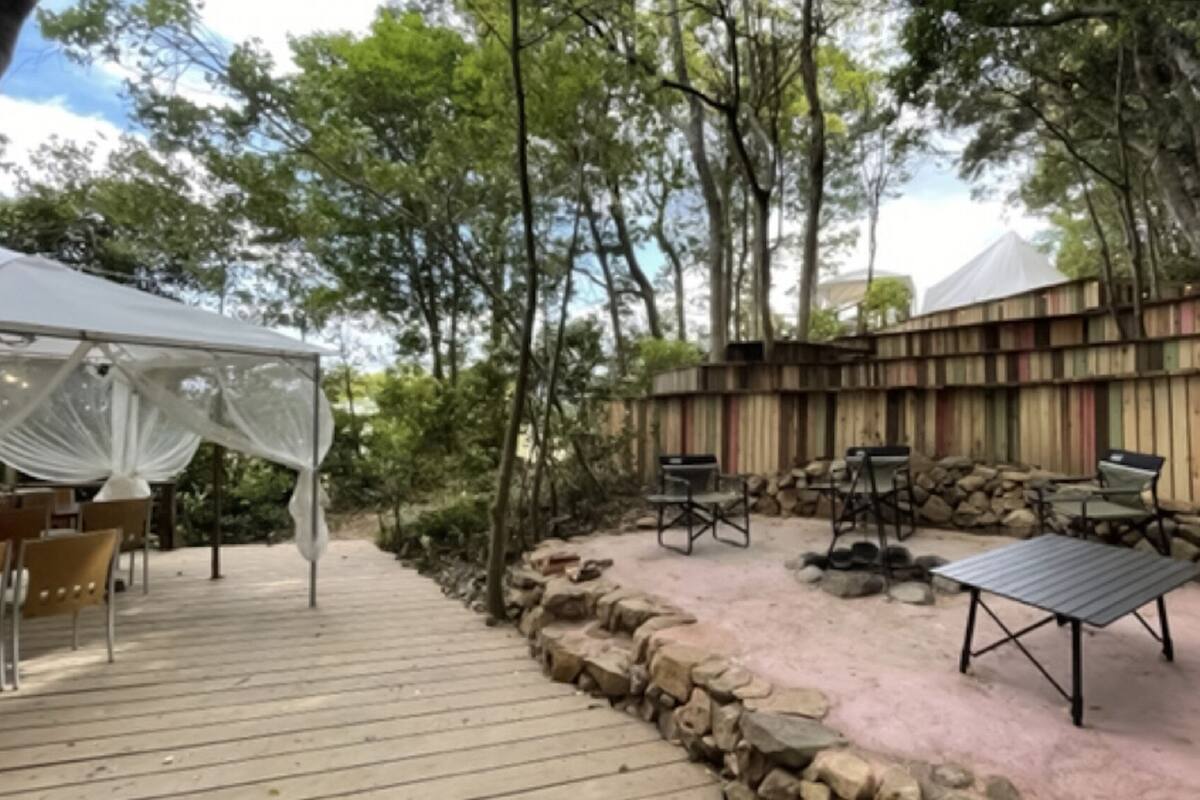 An outdoor patio with a white canopy, wooden deck, and seating area with chairs and a table.