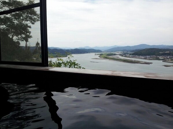 A view from a window overlooking a river with mountains in the distance.