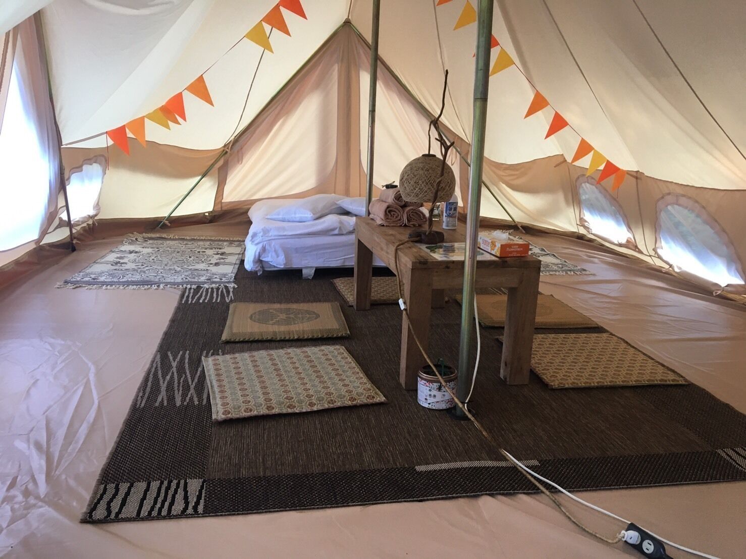 Ein Zelt mit einem Bett, Kissen, einem Tisch und Matten auf dem Boden.