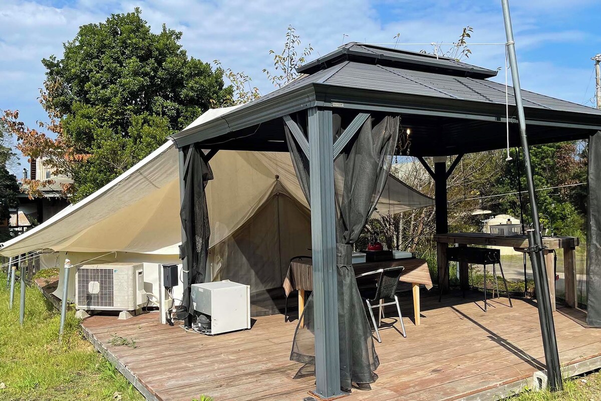 A covered outdoor area with a table and chairs, a grill, and an air conditioning unit.