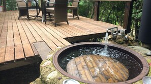 Een houten terras met buitenmeubilair, een jacuzzi en een fontein.