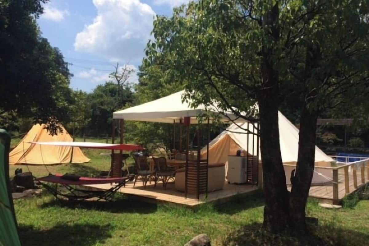 A camping site with tents, a covered dining area, and a pool.
