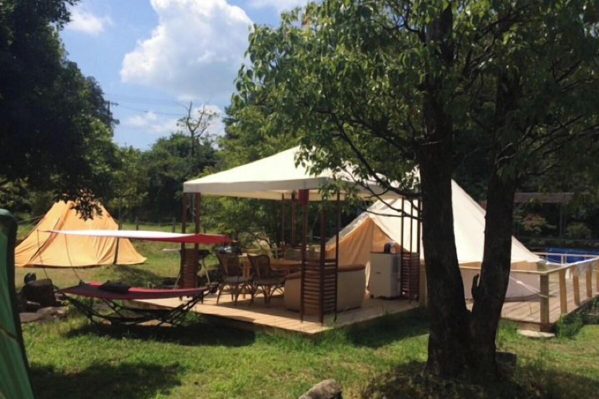 A camping site with tents, a covered dining area, and a pool.
