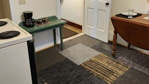 A compact kitchen with a stove, a coffee maker, and a table with a painting. - Large spacious room 5 minutes walk to historic downtown Manistee (Manistee)
