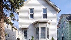 A two-story house with a front porch, a small front yard, and a tree to the left. - Large spacious room 5 minutes walk to historic downtown Manistee (Manistee)
