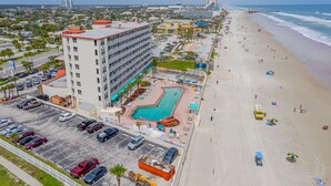 A hotel with a swimming pool, beach access, and a parking lot. - Stunning direct oceanfront views from your own balcony! (Daytona Beach)